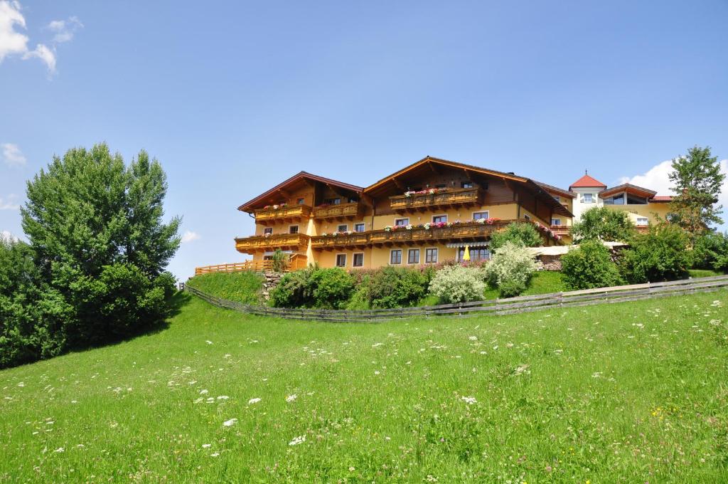 a large building on a hill with a green field at Haus Höllwart in Sankt Johann im Pongau