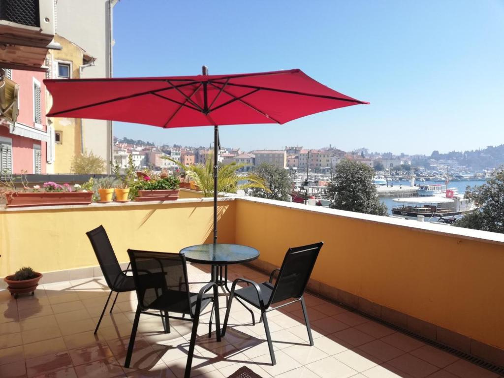 a table with chairs and a red umbrella on a balcony at Center of Rovinj, sea view apartment in Rovinj