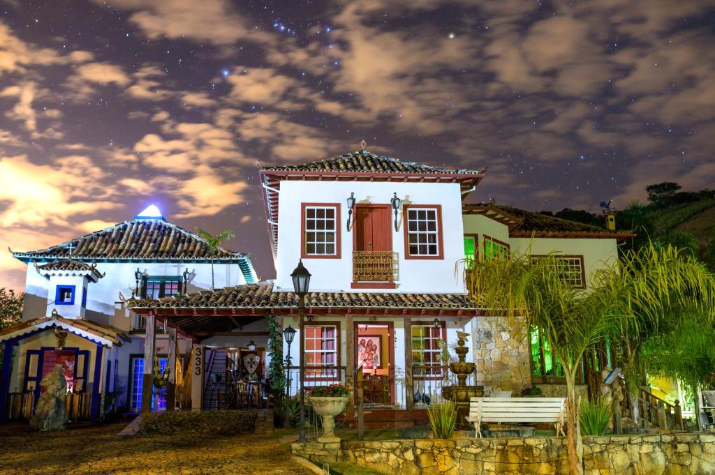 een wit huis met een bankje ervoor bij Templo do Sol Acomodações in Prados