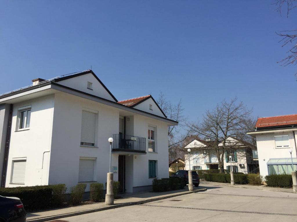 a white house with a balcony on a street at Apartments Matija Terme Ptuj in Ptuj