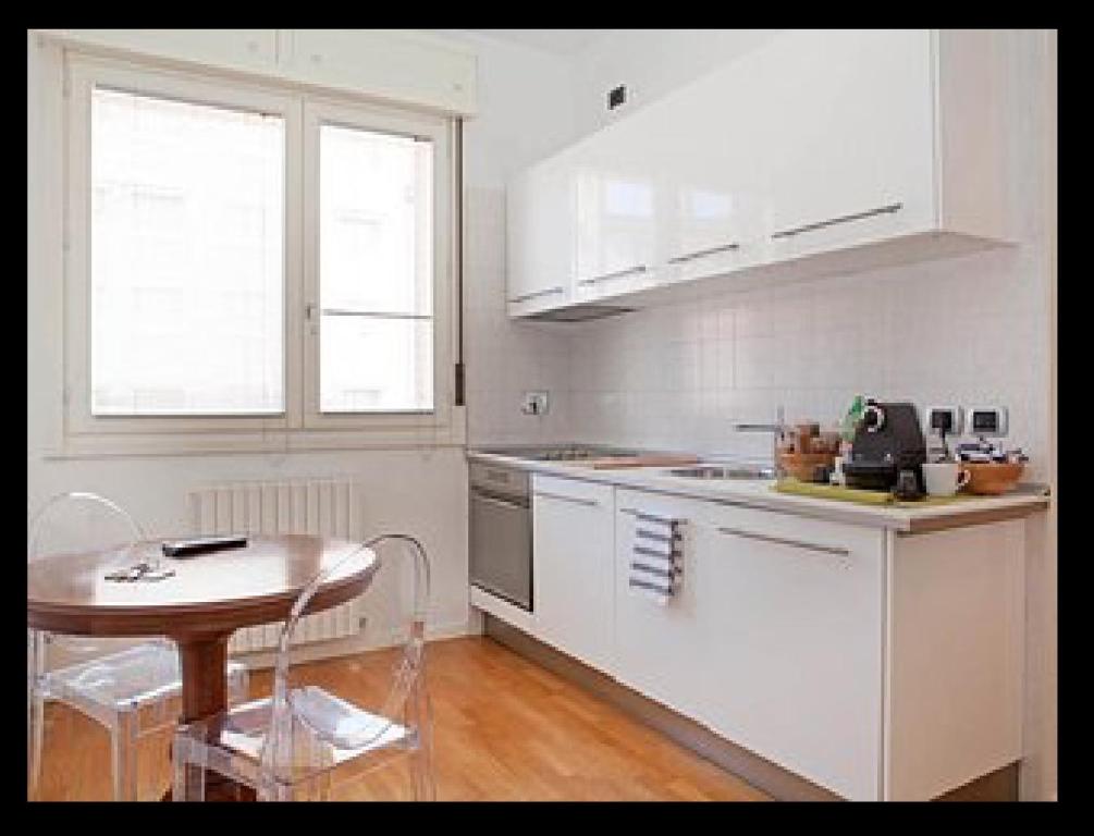 a kitchen with white cabinets and a table and a table and chair at Room Touch And Go in Bologna