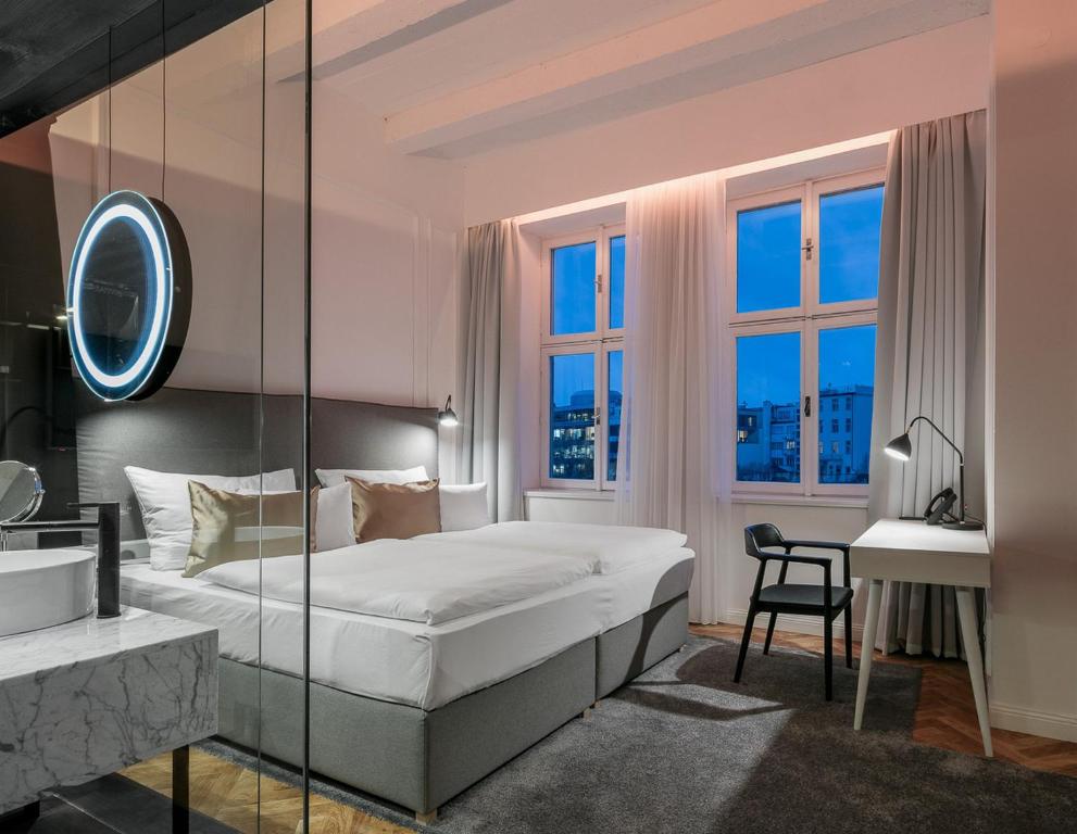 a bedroom with a bed and a desk and windows at Pytloun Boutique Hotel Prague in Prague