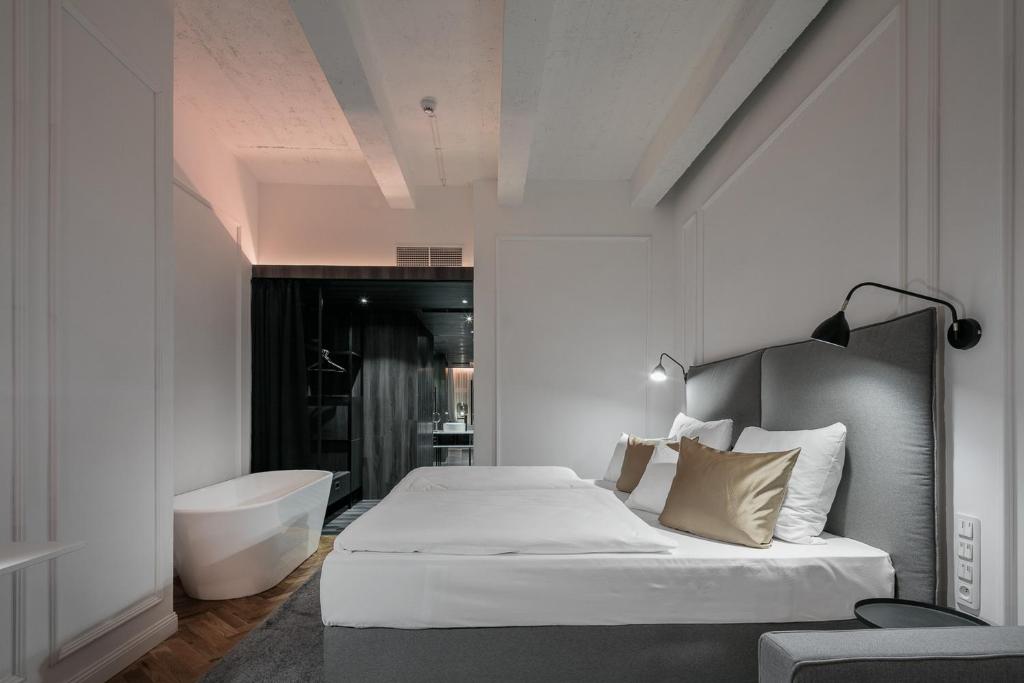 a bedroom with a tub and a bed and a sink at Pytloun Boutique Hotel Prague in Prague