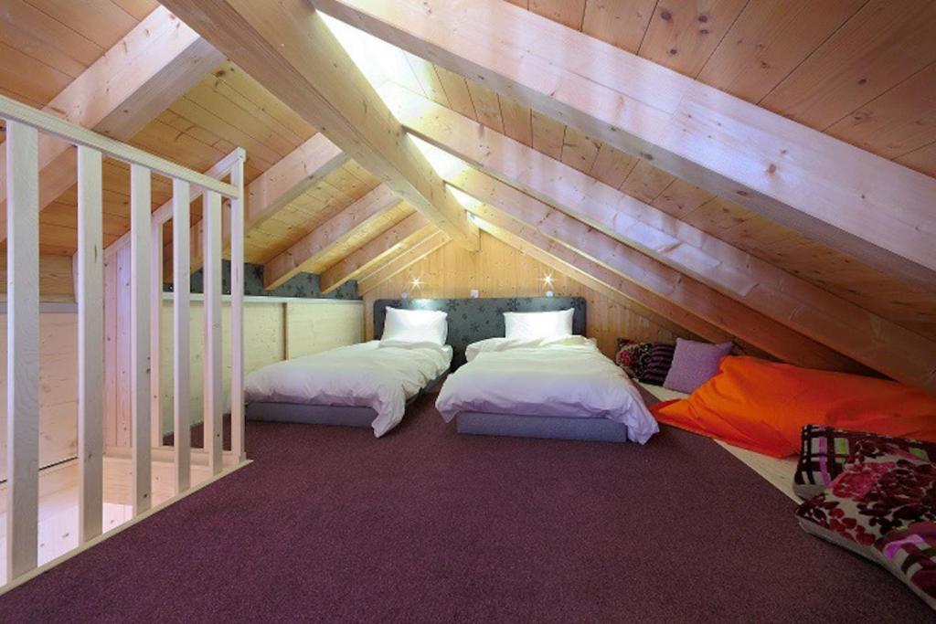 a attic room with two beds and a staircase at Gîte du Bief de la Chaille in Les Rousses