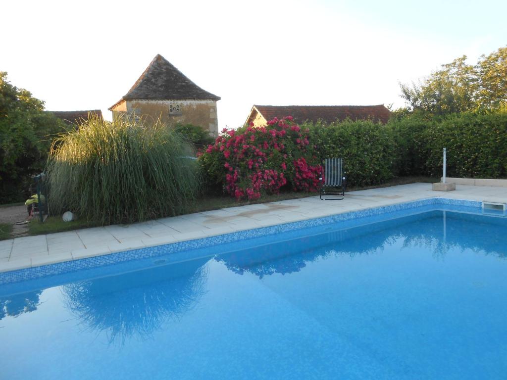 een zwembad met een stoel en bloemen bij CHAMBRES d'HOTES LE ROUSSEL in Le Buisson de Cadouin