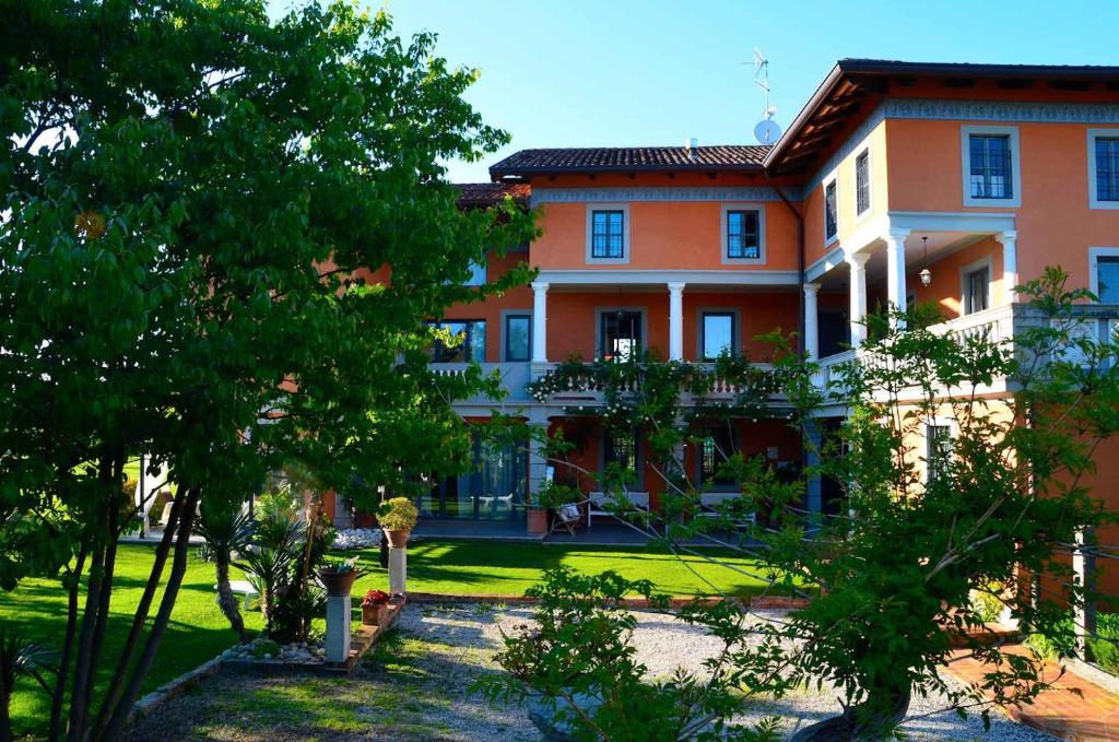 un grand bâtiment oranger avec des arbres devant lui dans l'établissement Le Rondini, à Grions del Torre