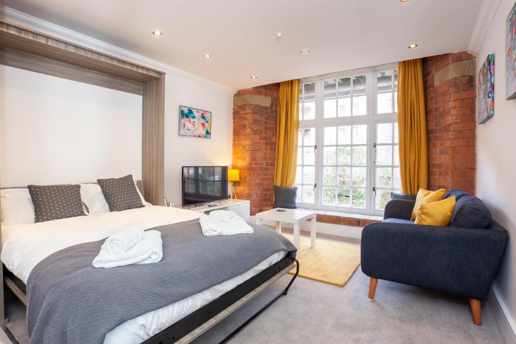 a bedroom with two beds and a chair and a window at Cocoa Suites Luxury Apartments in York