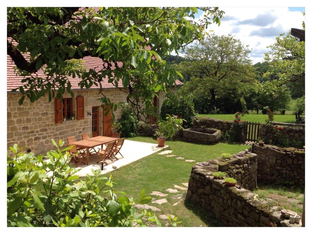 a stone house with a picnic table in the yard at A L'Ombre du Tilleul in Comiac