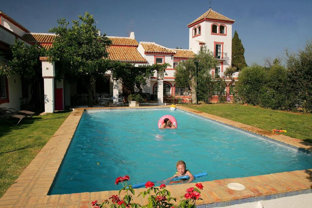 een meisje zwemmend in een zwembad in een huis bij Cortijo El Triguero N-398 Ctra Carmona – El Viso del Alcor Km 18 in Carmona