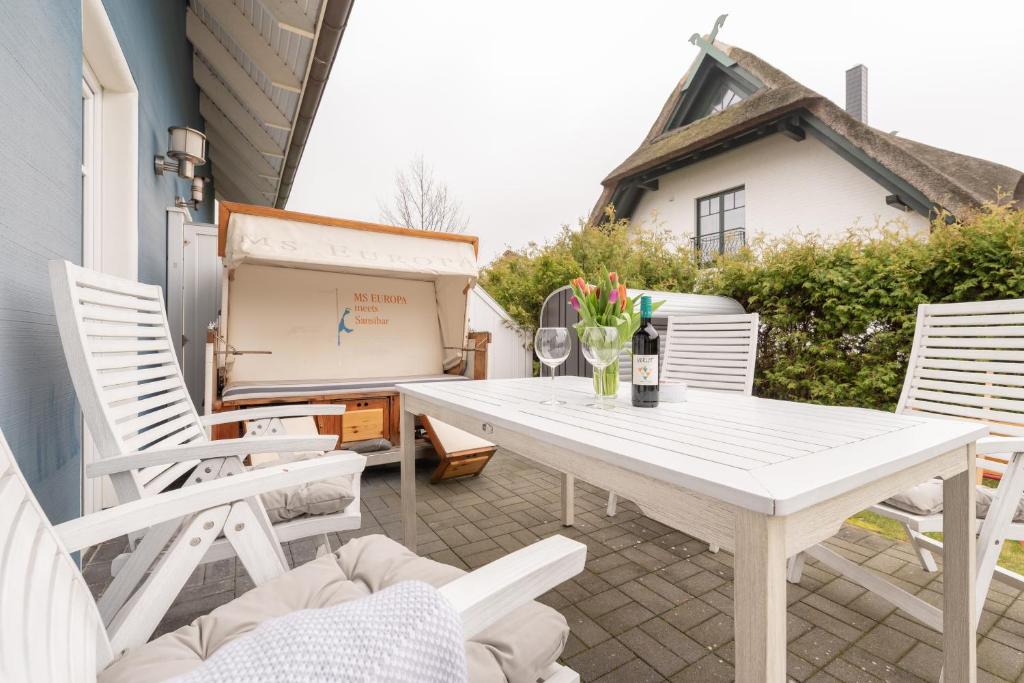 einen weißen Tisch und Stühle auf einer Terrasse in der Unterkunft Ferienwohnungen Parkstraße in Börgerende-Rethwisch