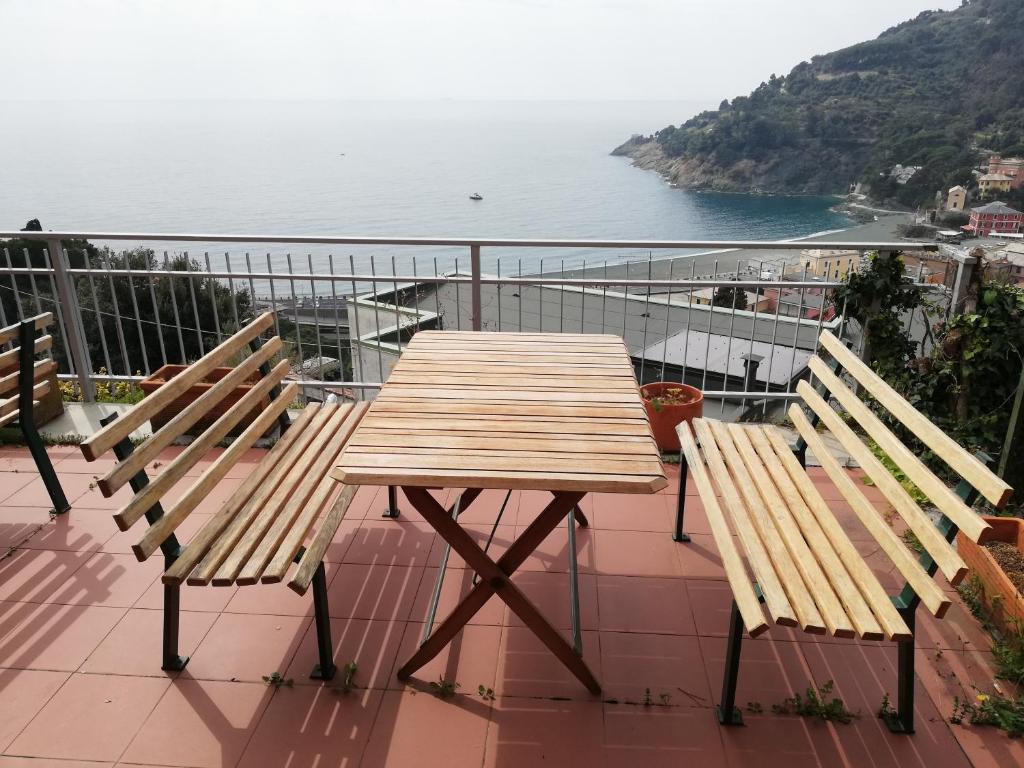 a wooden table and two benches on a balcony overlooking the water at Bonassola Vista Mare in Bonassola