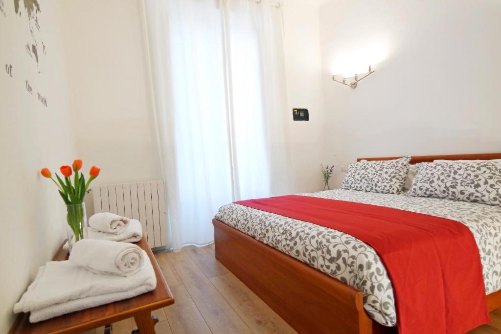 a bedroom with a bed with a red blanket and towels at LikeHome Milano - Via Crema in Milan