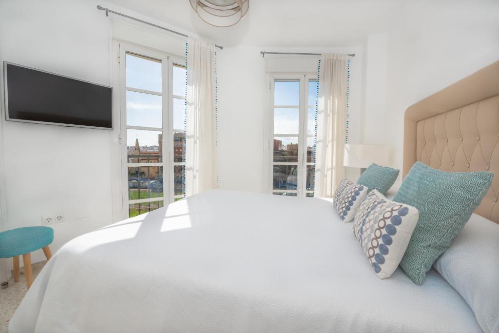 a white bedroom with a bed and windows at Myramar Premium Center in Málaga