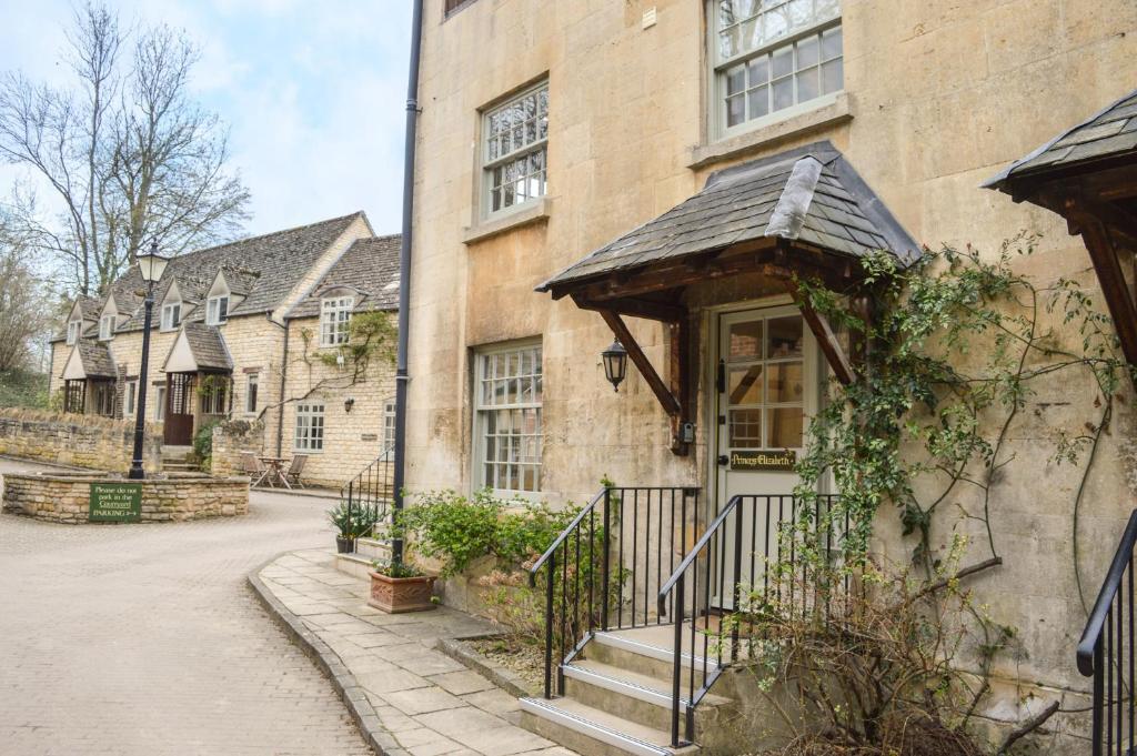 una vieja casa de piedra con una puerta y una calle en Princess Elizabeth, en Winchcombe