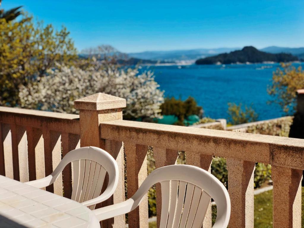 2 stoelen en een tafel op een balkon met uitzicht op het water bij Apartamentos Raxo Mar in Poio