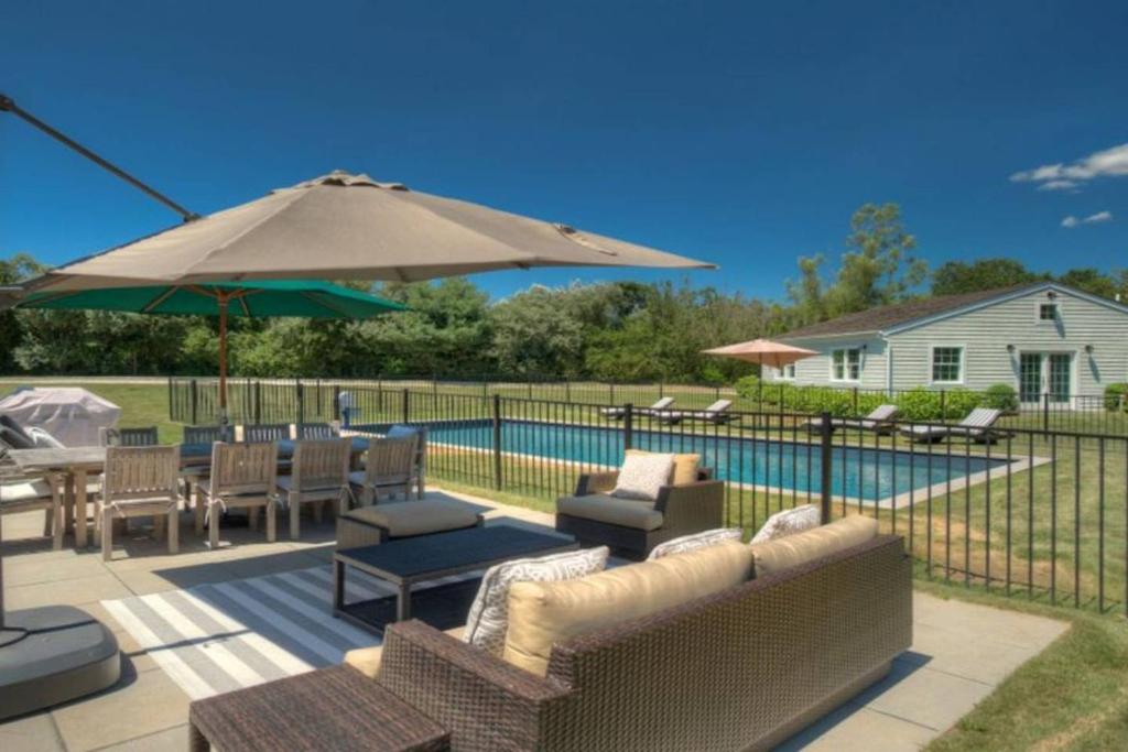 un patio con sofás, una sombrilla y una piscina en Villa Bridgehampton village, en East Hampton
