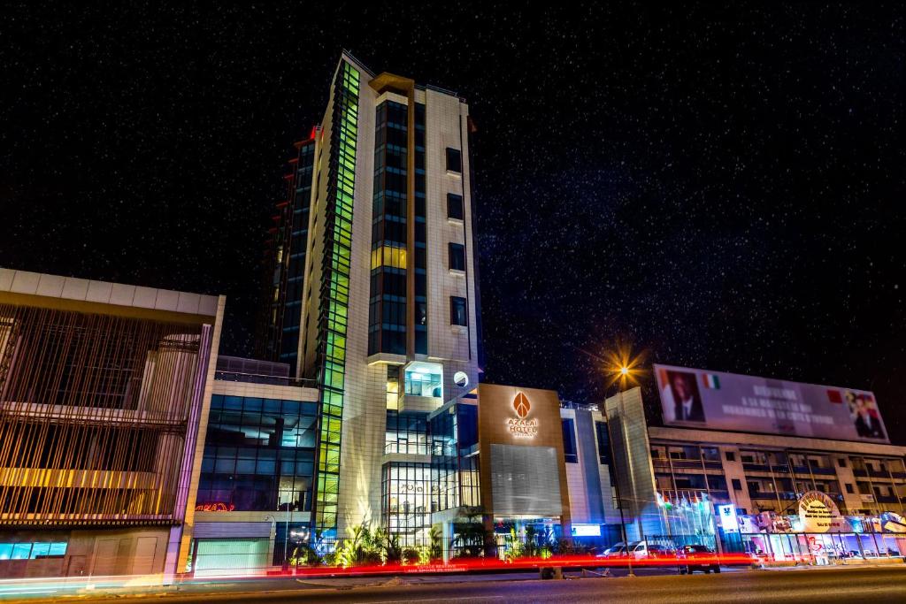 a tall building at night with a street in front of it at Azalaï Hôtel Abidjan in Abidjan