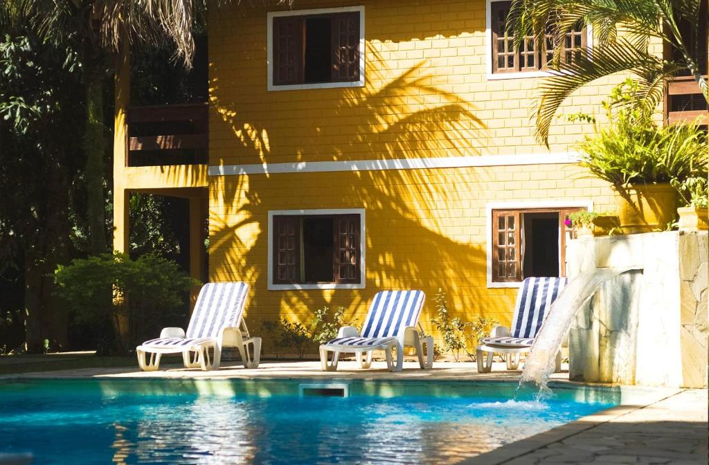 three chairs sitting next to a house with a swimming pool at Condomínio Boiçucanga in Boicucanga