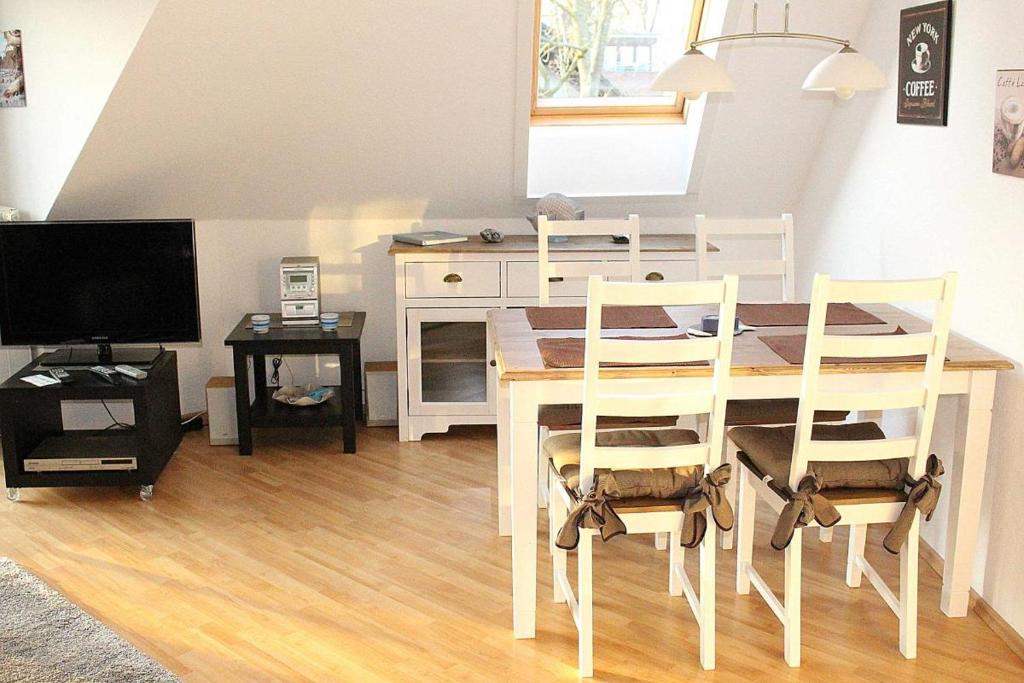 a dining room with a table and chairs and a television at Apartmentvermittlung Mehr als Meer - Objekt 74 in Niendorf