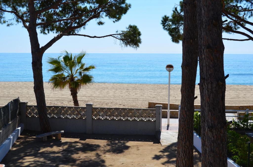 vistas a una playa con un banco y árboles en La Torre - Villa Rosamar Beach, en Cambrils