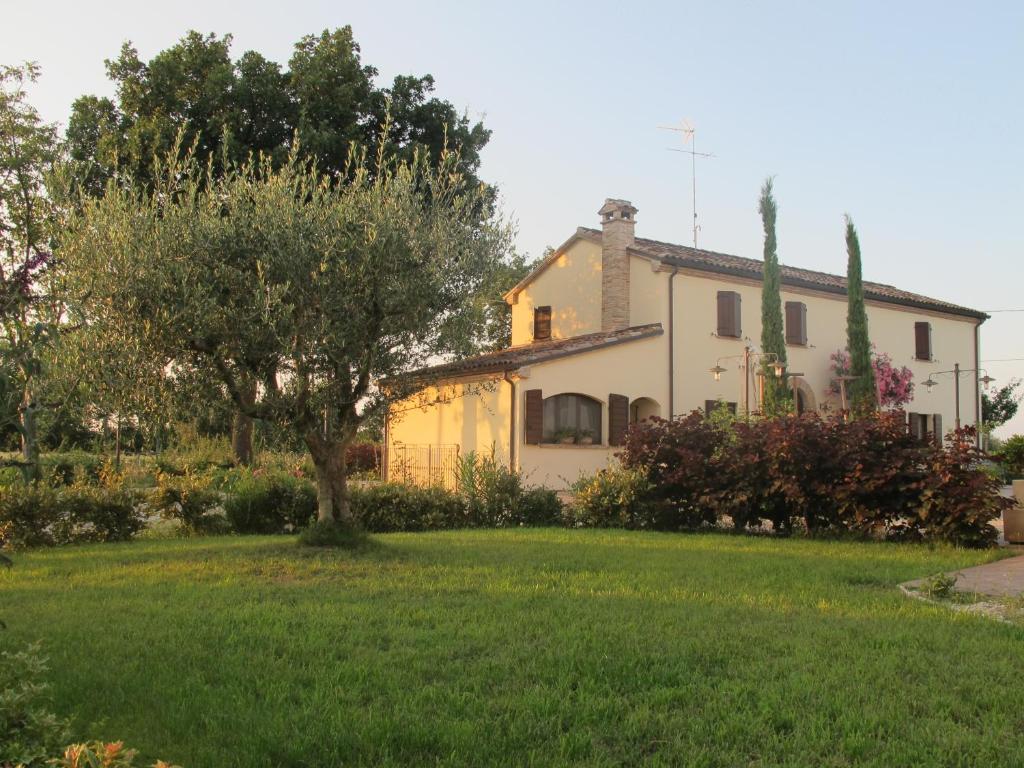 une maison jaune avec un arbre dans une cour dans l'établissement FATTORIA DELLA BILANCIA, à San Giovanni in Marignano