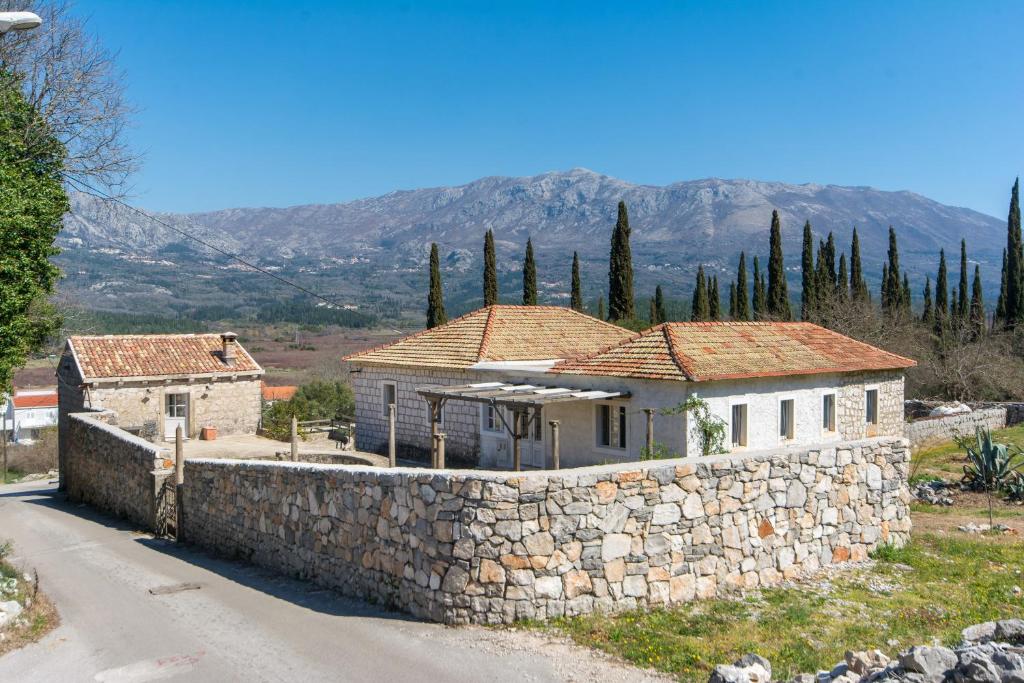 une maison avec un mur en pierre à côté d'une route dans l'établissement Koraćeva kuća, à Gruda