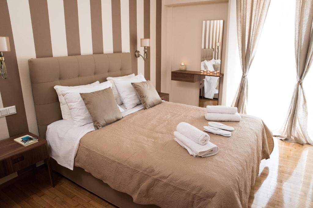 1 dormitorio con 1 cama grande y toallas. en AT.thea ATHENS BOUTIQUE APARTMENTS, en Atenas