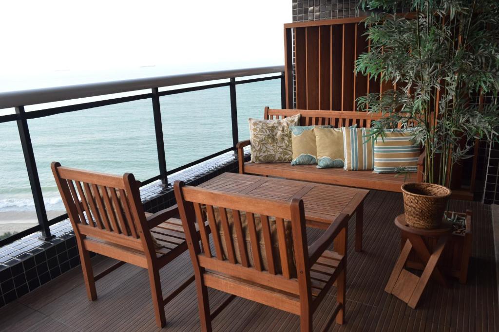 Un balcón con 2 sillas y una mesa y un banco de madera. en Grupo Vip Landscape Fortaleza, en Fortaleza