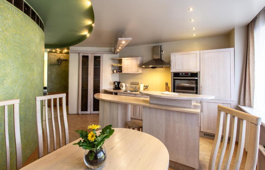 a kitchen with a table with a vase of flowers on it at Gerda Apartments in Druskininkai