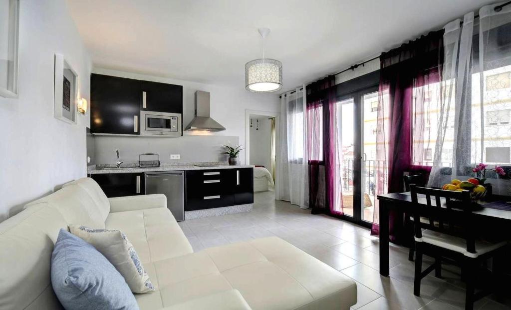 a living room with a white couch and a kitchen at Apartamentos Villa Serali Parking Gratis in Ronda