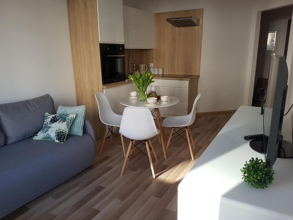 a living room with a couch and a table and chairs at Caskada Modern Apartment in Słupsk
