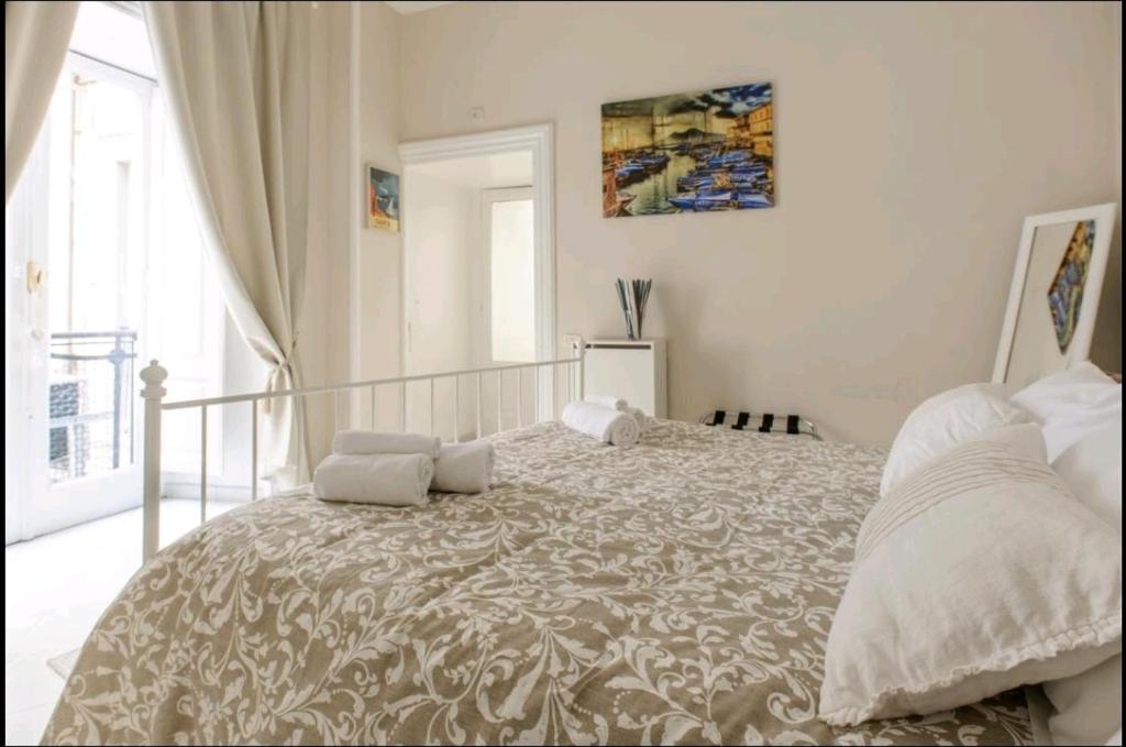 a white bedroom with a large bed with white pillows at Borgo Santa Lucia Apartment in Naples