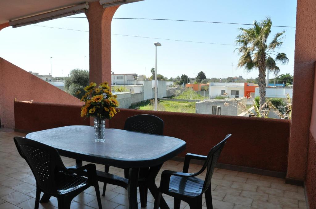 einen Tisch mit Stühlen und eine Vase mit Blumen auf dem Balkon in der Unterkunft Casa vacanza San Foca in San Foca