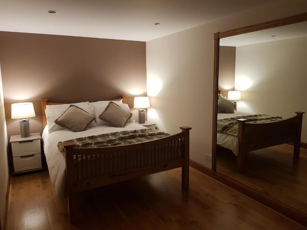 een slaapkamer met een bed en een grote spiegel bij The Smiddy Suite in Ellon