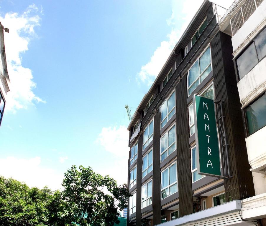 a building with a green sign on the side of it at Nantra Silom in Bangkok