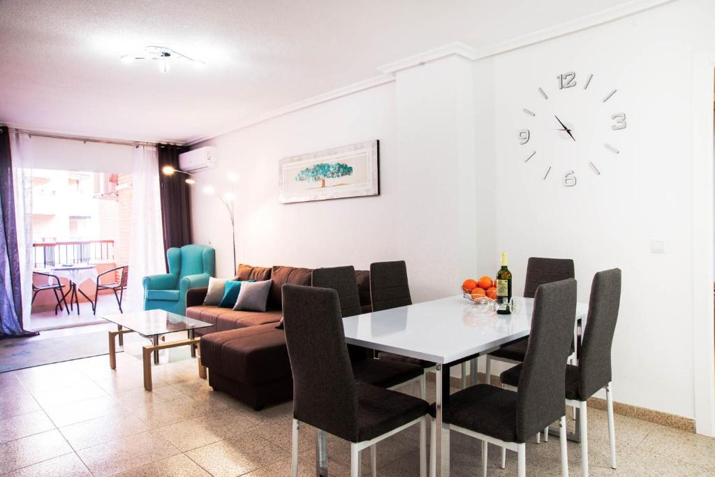 sala de estar con mesa, sofá y reloj en Holiday Royal Suite Concordia, en Torrevieja