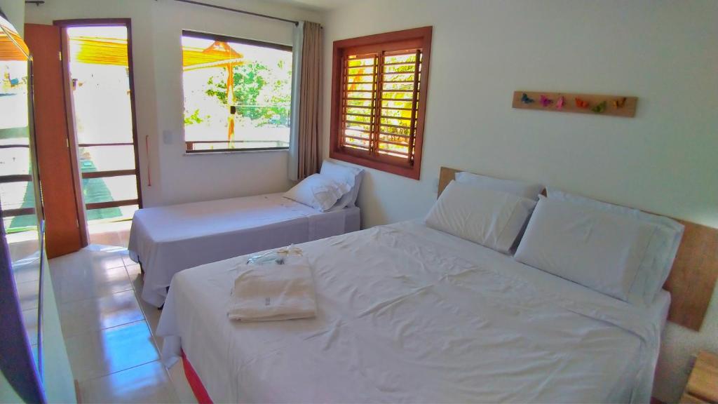 a bedroom with a bed and a couch and a window at Corvina Suites in Praia do Forte