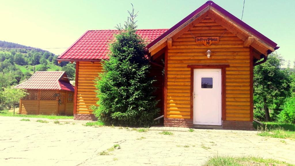 a small wooden cabin with a white door at Смерековий двір in Yaremche