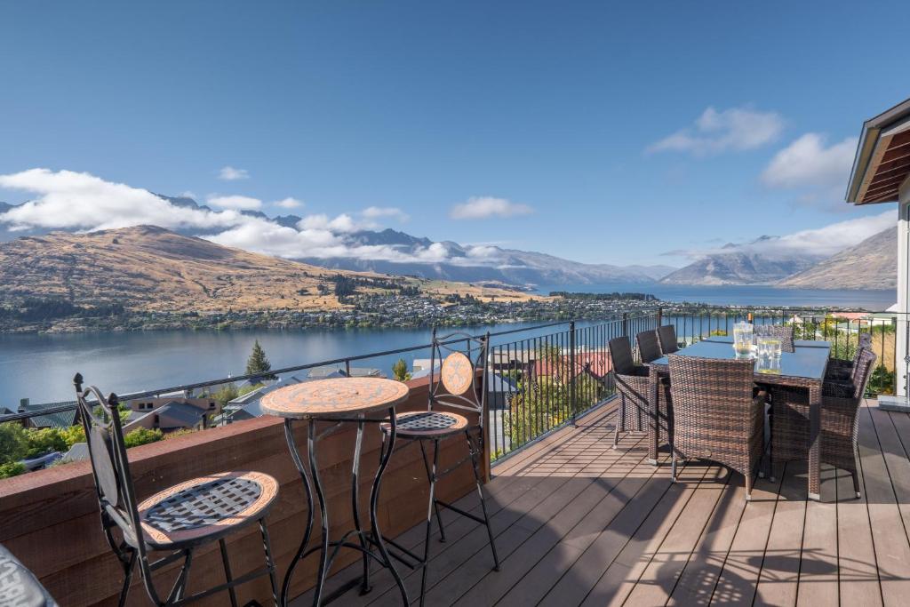 einen Balkon mit Tischen und Stühlen und Blick auf das Wasser in der Unterkunft Oriwa View in Queenstown