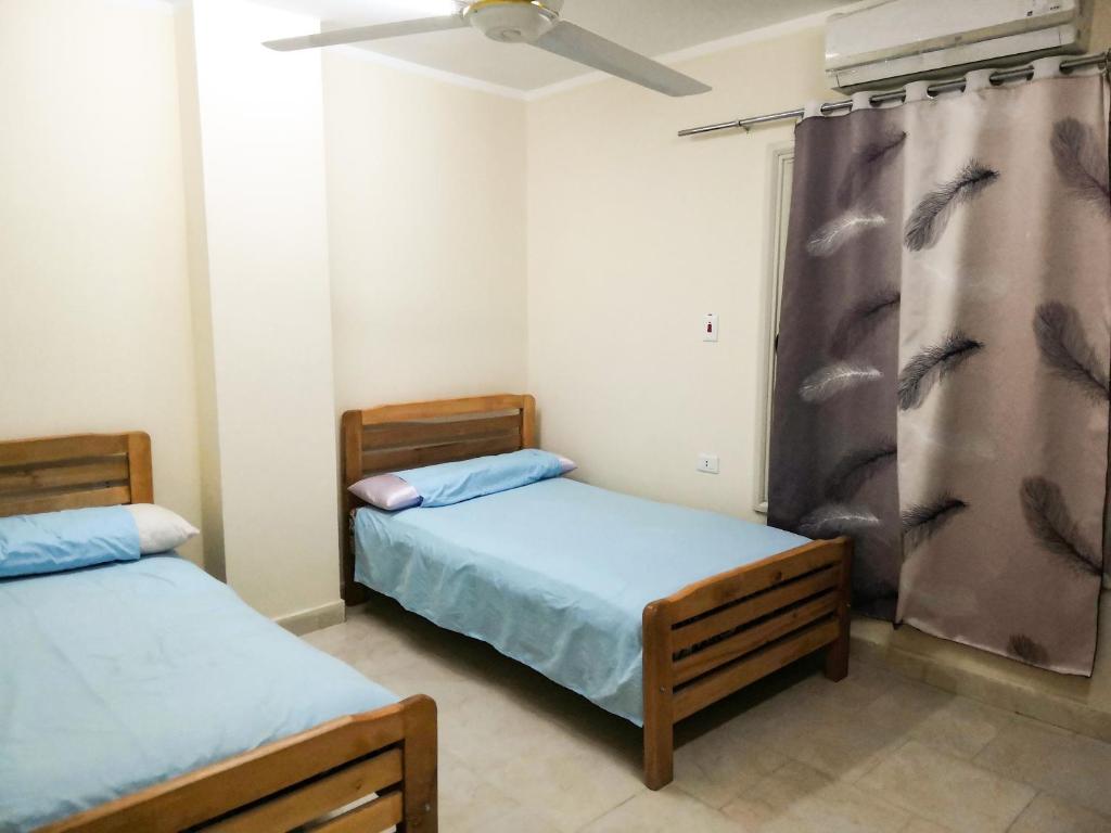 a bedroom with two beds and a ceiling fan at Happy Days in Hurghada