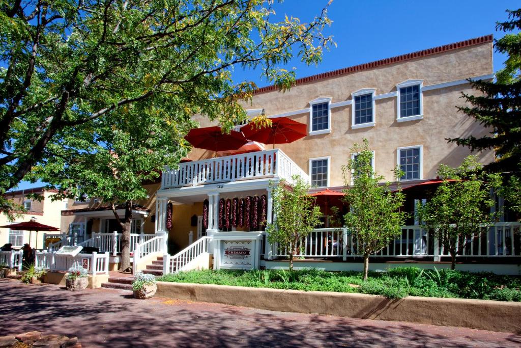 a large house with a porch and a white fence at Hotel Chimayo de Santa Fe in Santa Fe