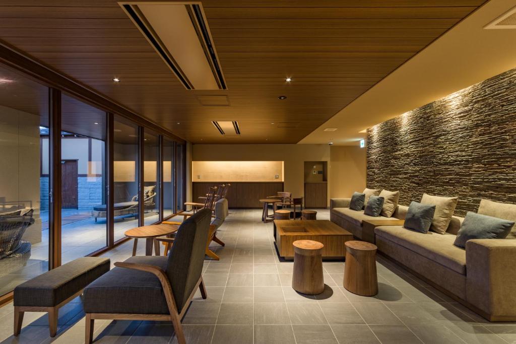 a living room with couches and tables and windows at Oike Hotel in Fujikawaguchiko