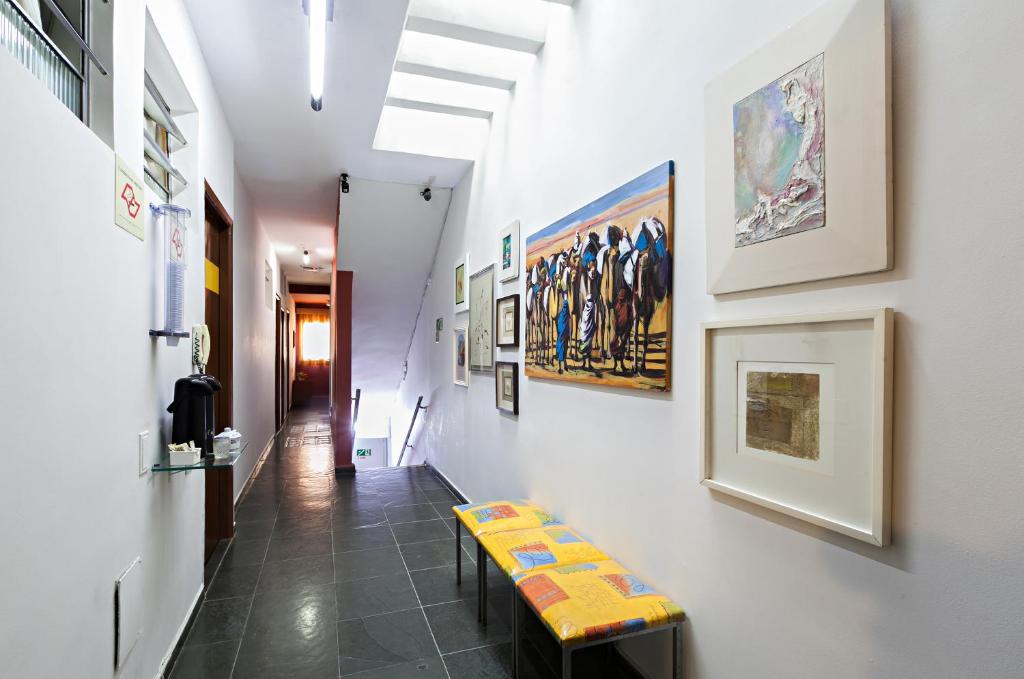 a hallway with a bench and paintings on the wall at Hotel Econômico ao lado do Metrô in São Paulo