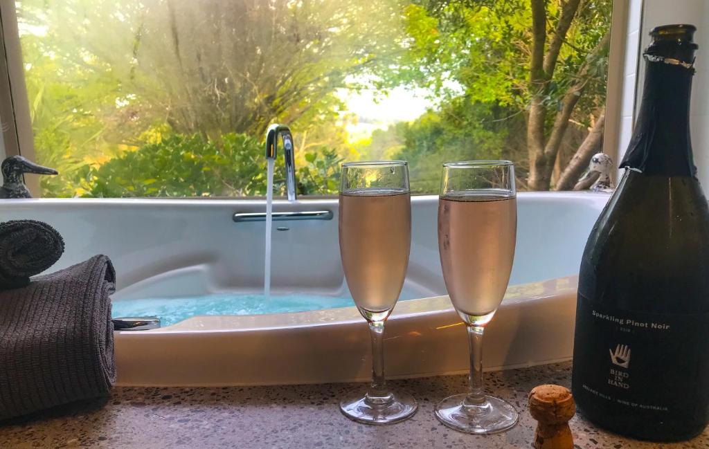 Dos copas de champán junto a la bañera. en Adelaide Hills Retreats, en Balhannah