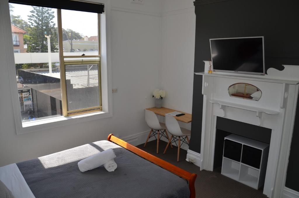 a bedroom with a fireplace and a bed with a television at Sandy Bottoms Guesthouse in Sydney