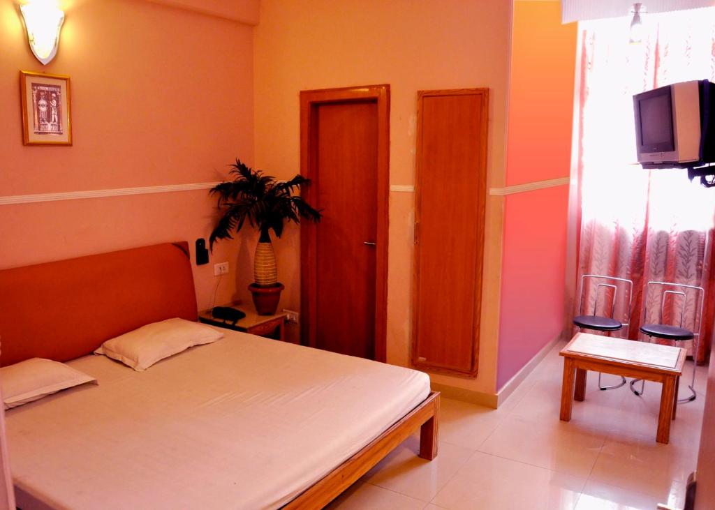 una camera con un letto e una televisione di Hotel Queen a Haridwār