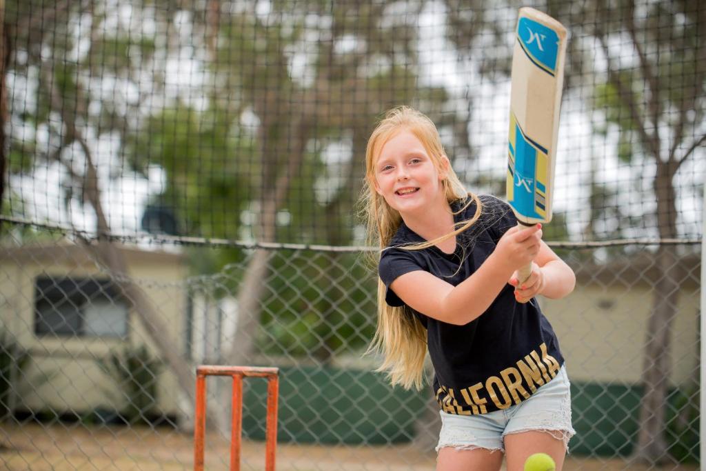 a young girl is holding a baseball bat at Ingenia Holidays Torquay Australia in Torquay