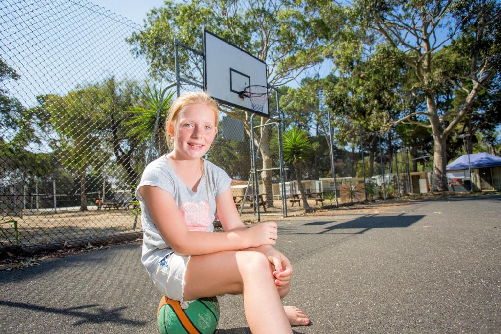 a young girl sitting on a ball on a basketball hoop at Ingenia Holidays Torquay Australia in Torquay