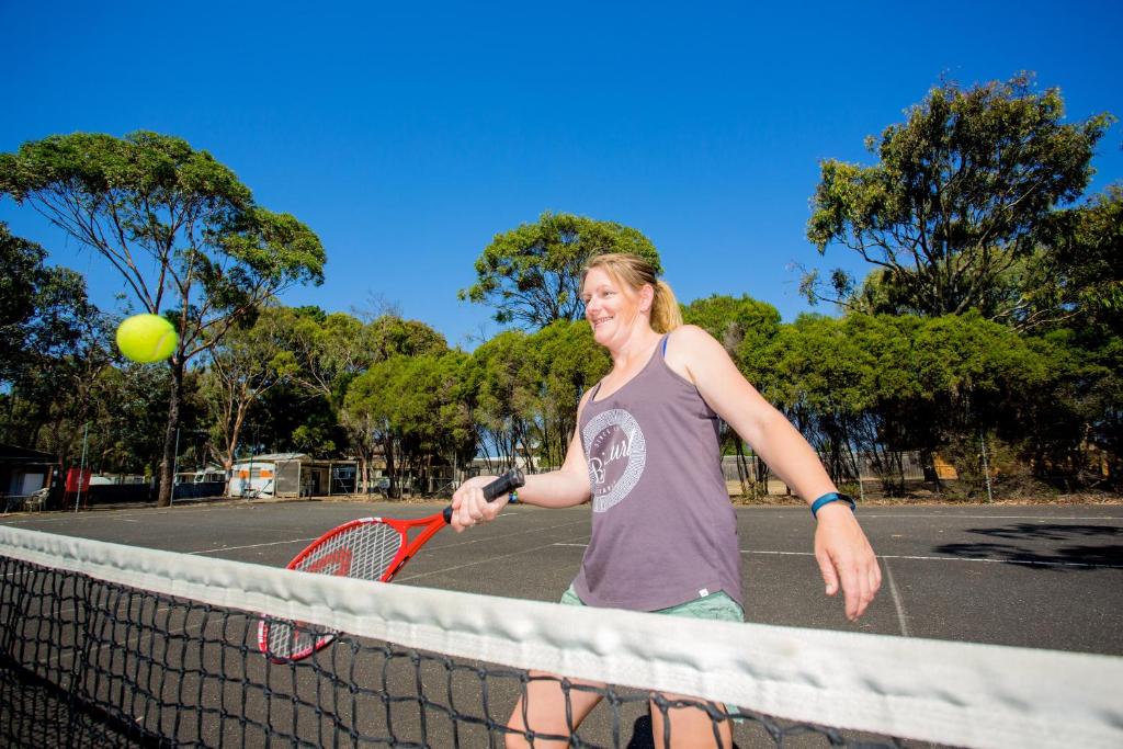 a woman holding a tennis racket on a tennis court at Ingenia Holidays Torquay Australia in Torquay