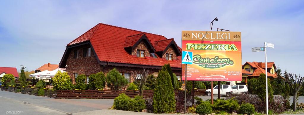 une maison avec un panneau devant elle dans l'établissement Noclegi Cameleon, à Słupca